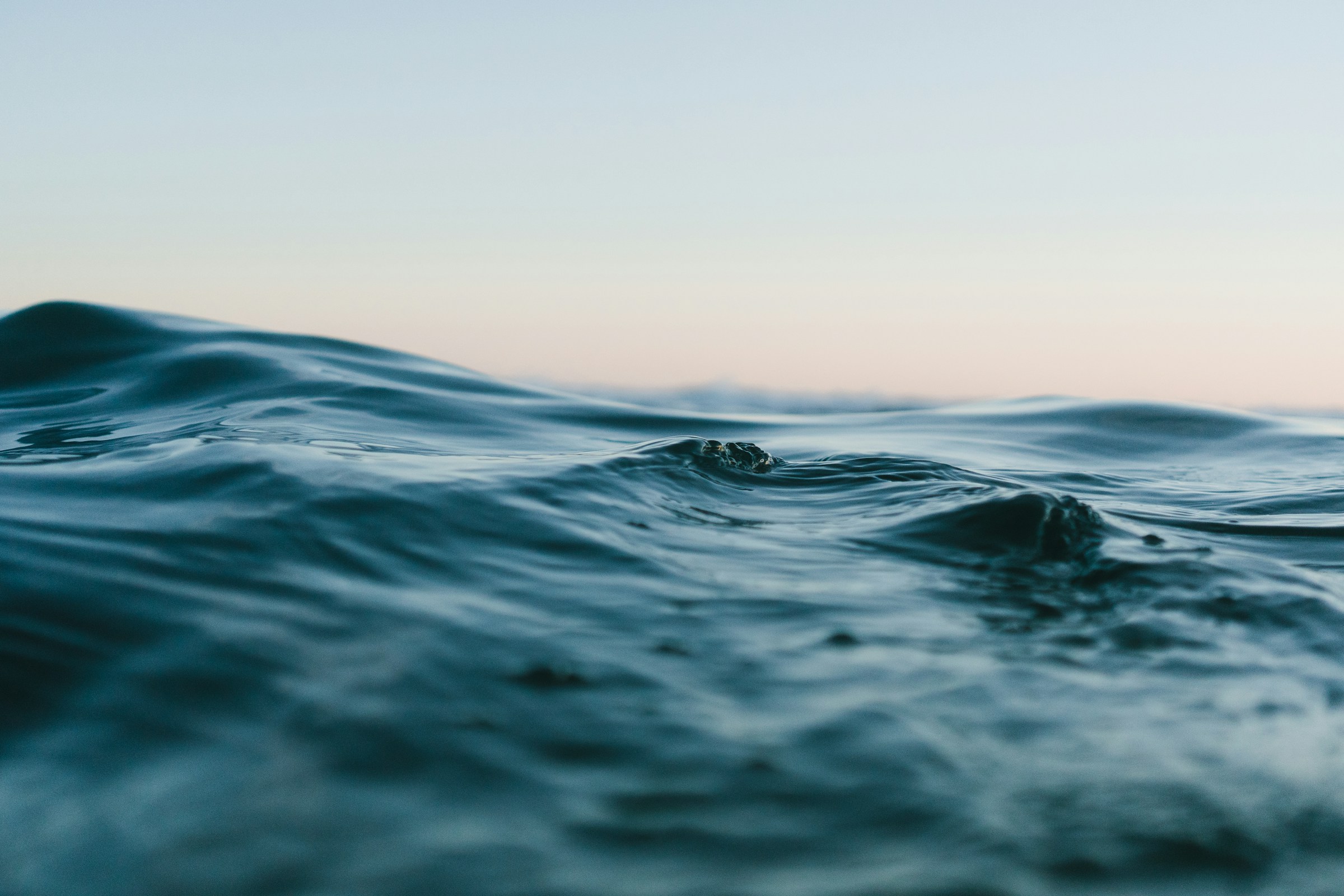 Quiet ocean swells beneath a soft, open sky